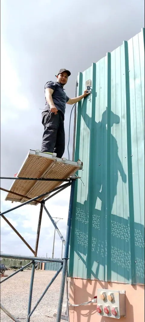 Électricien installant un équipement sur bardage métallique en hauteur