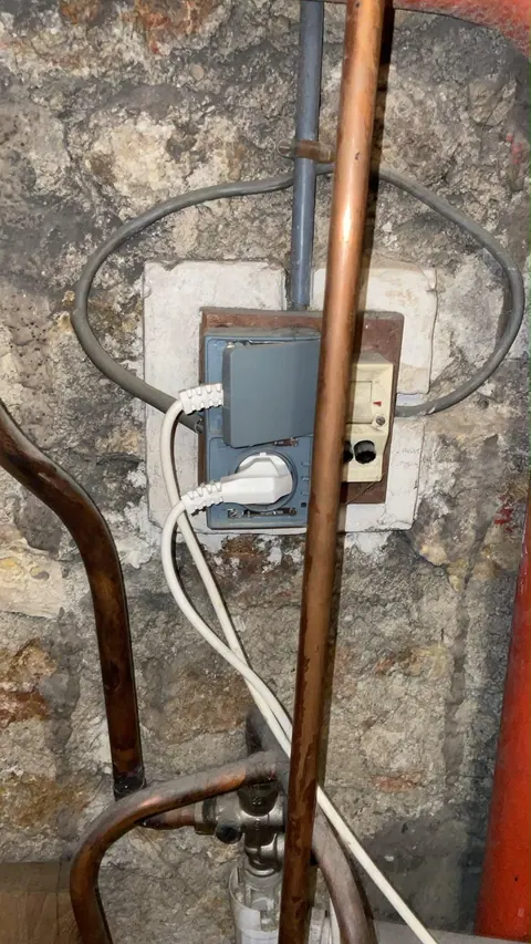 Prise et boîtier électriques vétustes sur mur en pierre